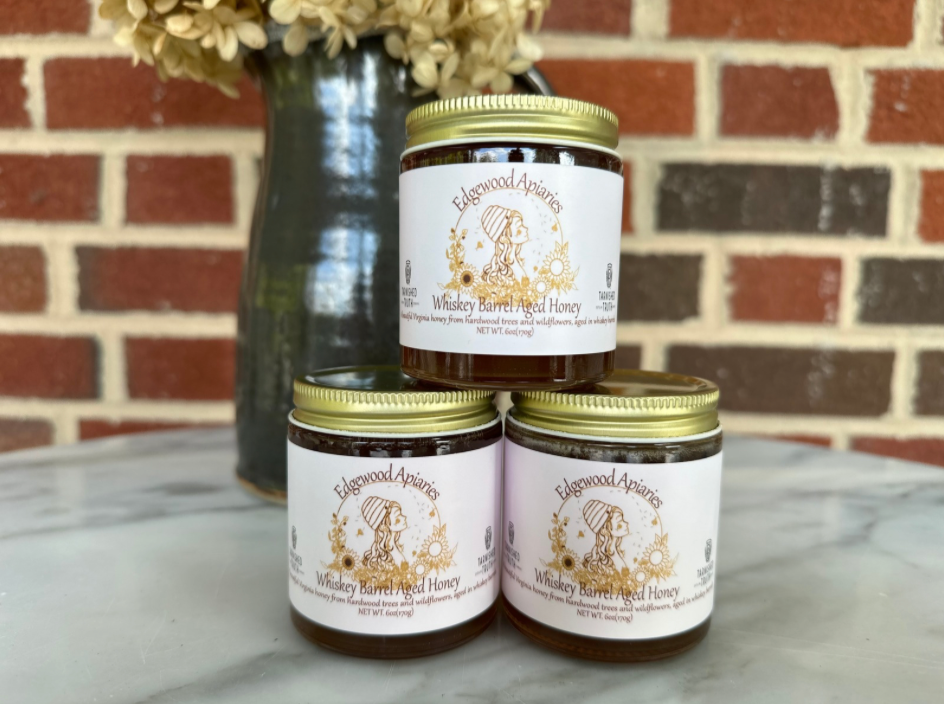 Three 6 oz jars of Edgewood Apiaries Whiskey Barrel Aged Honey stacked on marble