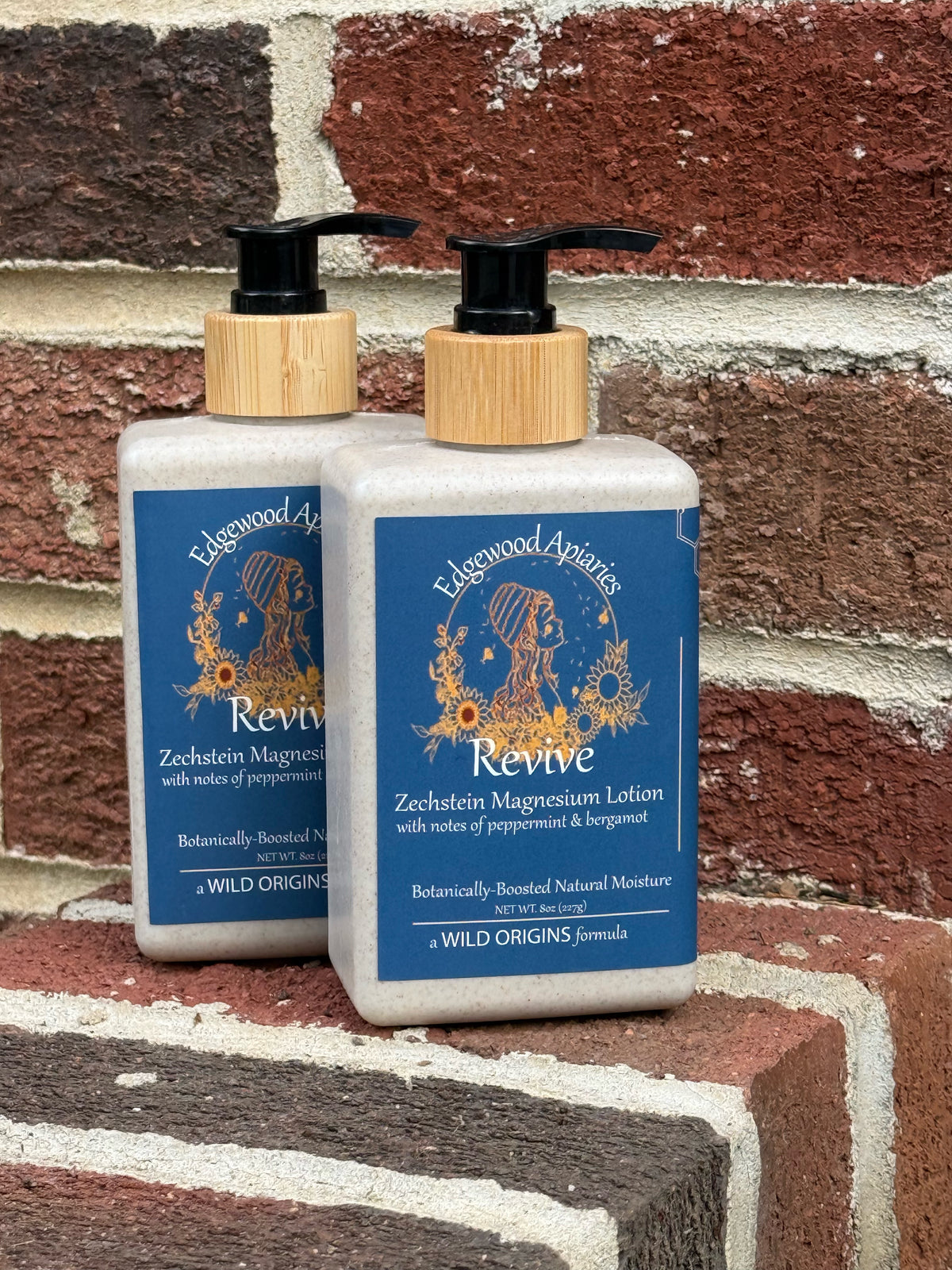 Edgewood Apiaries Revive Zechstein Magnesium Lotion with peppermint and bergamot, two pump bottles on a brick step