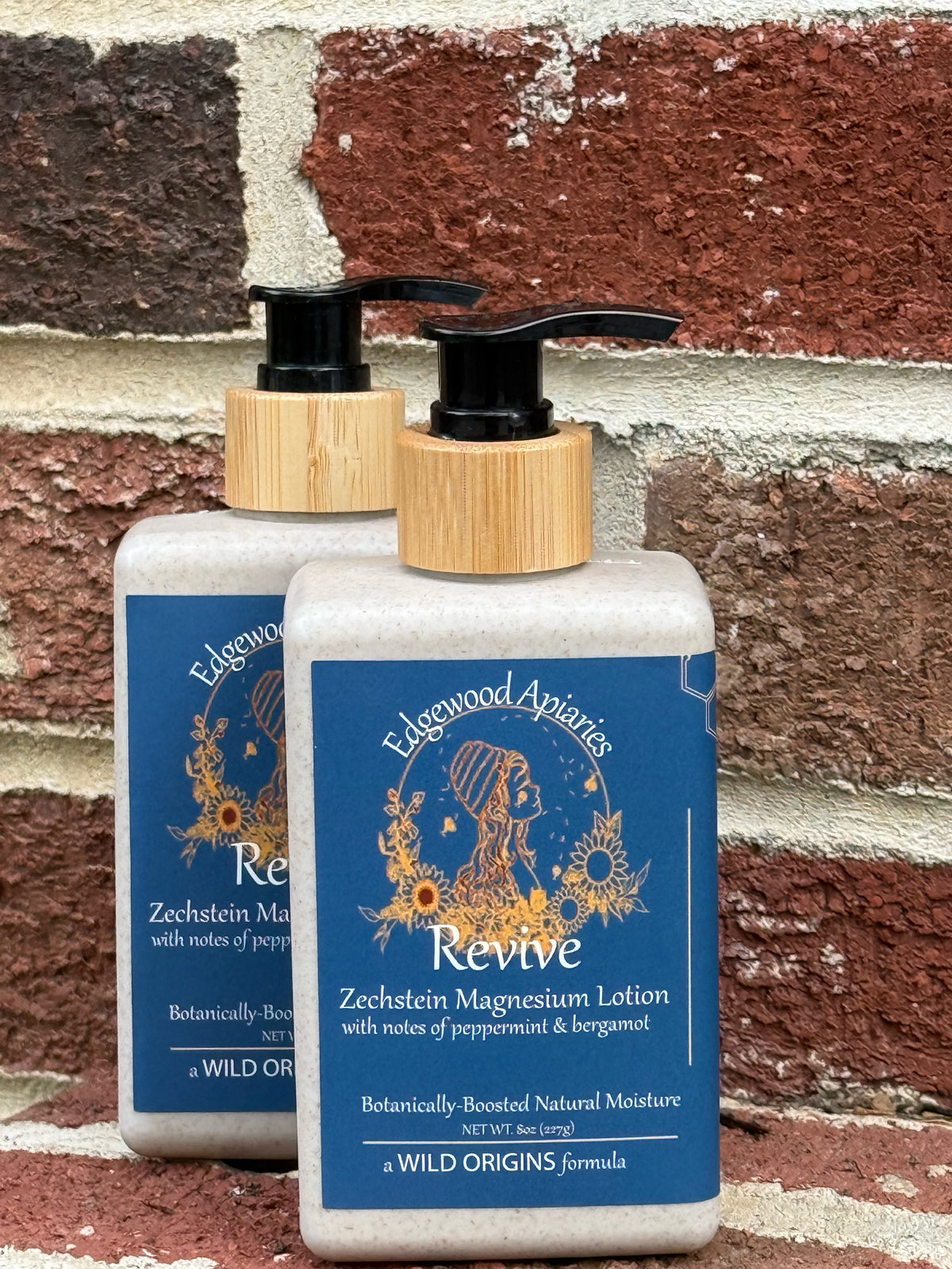 Revive magnesium lotion 8 oz wheat straw bottles with bamboo pumps against a red brick wall